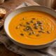 Roasted Pumpkin and Red Lentil Soup in a rustic bowl with toasted pumpkin seeds, olive oil and crusty bread